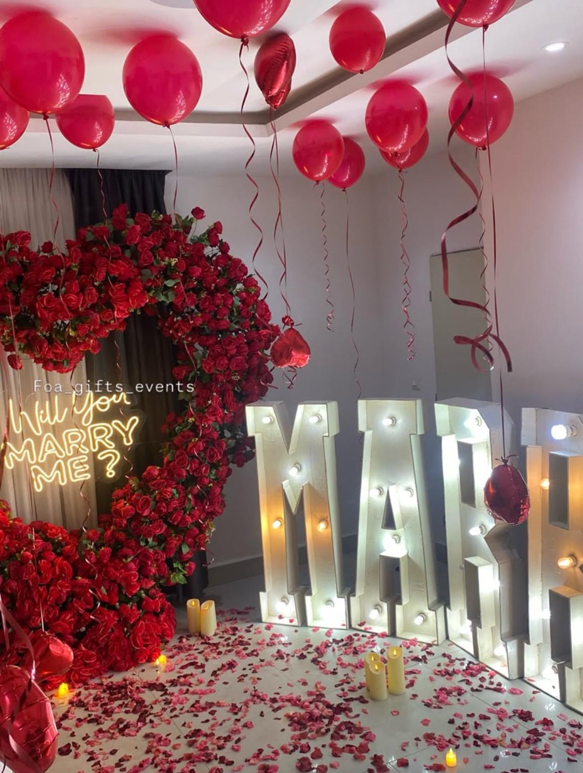 Hotel-style proposal scene with red balloons and a floral heart