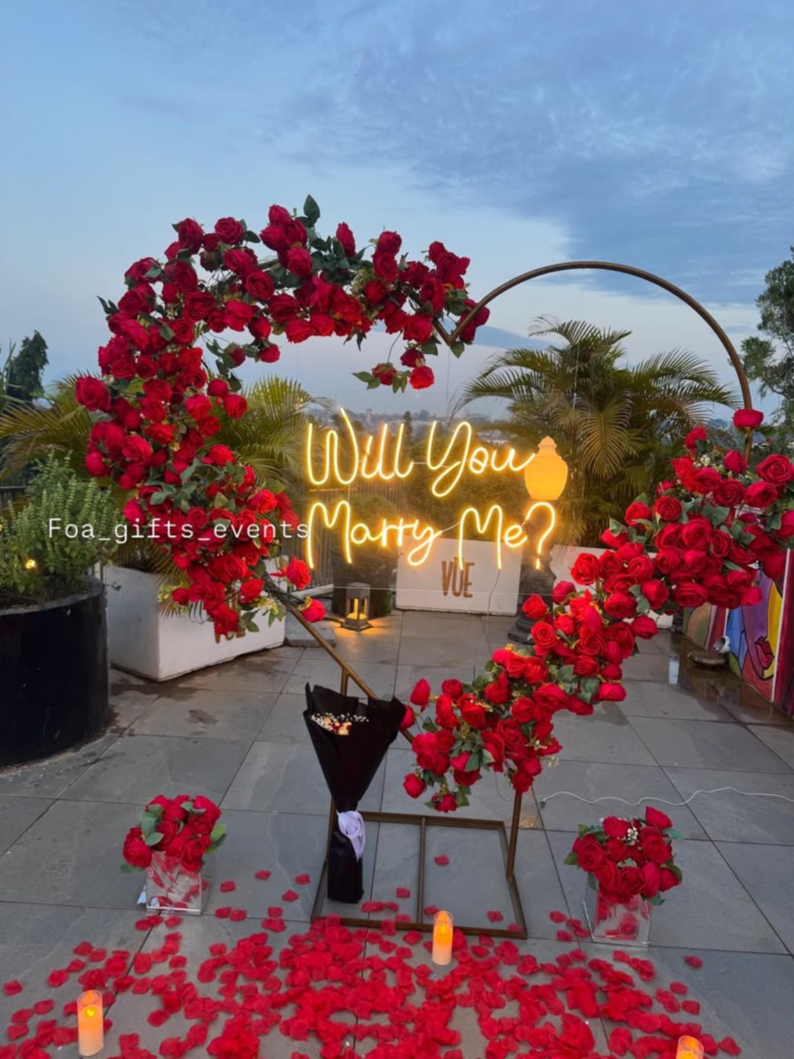 Outdoor proposal display with a red floral heart and illuminated question