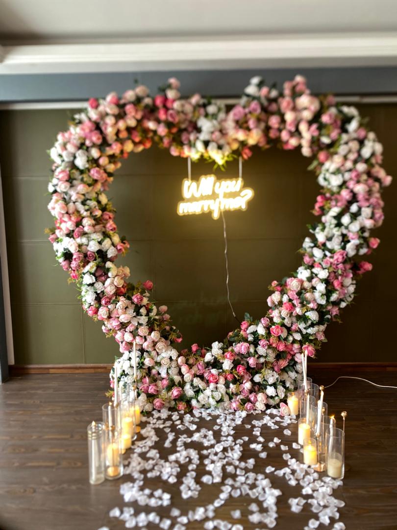Romantic anniversary surprise setup with pink floral heart arch and candles Abuja Nigeria FOA_gifts
